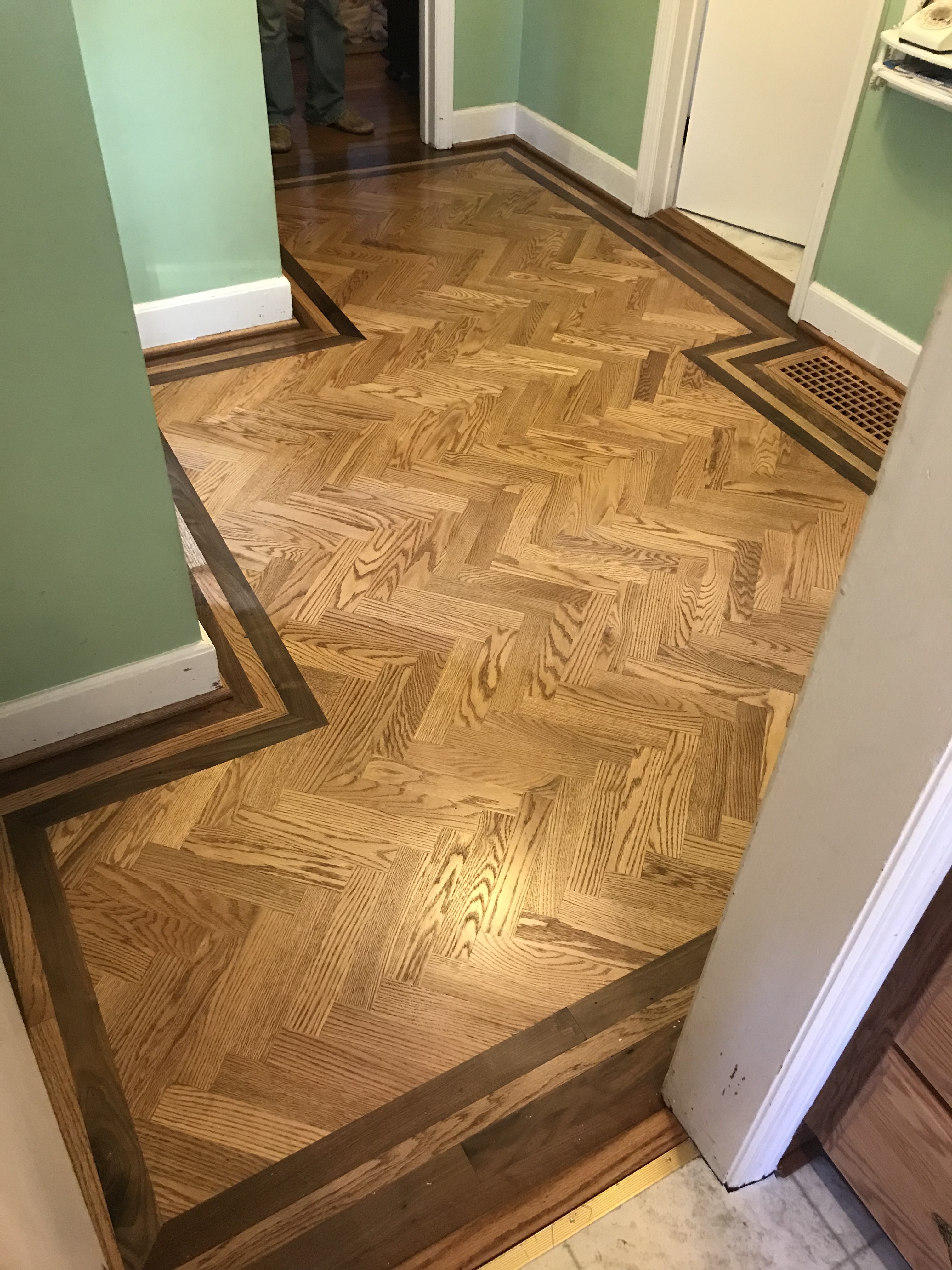 Custom herringbone oak parquet flooring with dark walnut border inlay in a home hallway