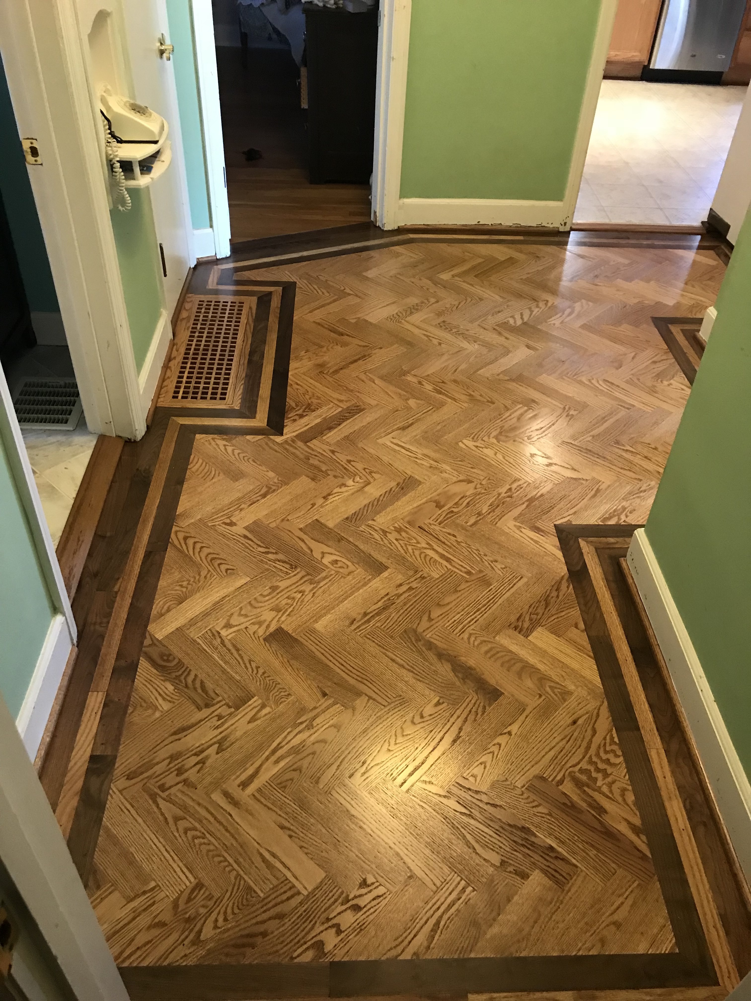 Herringbone parquet hardwood flooring extending through a hallway, viewed from above