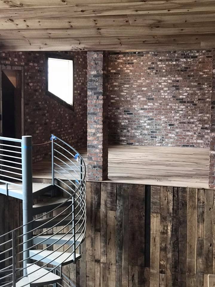 Finished room with rustic wood flooring beside exposed brick walls