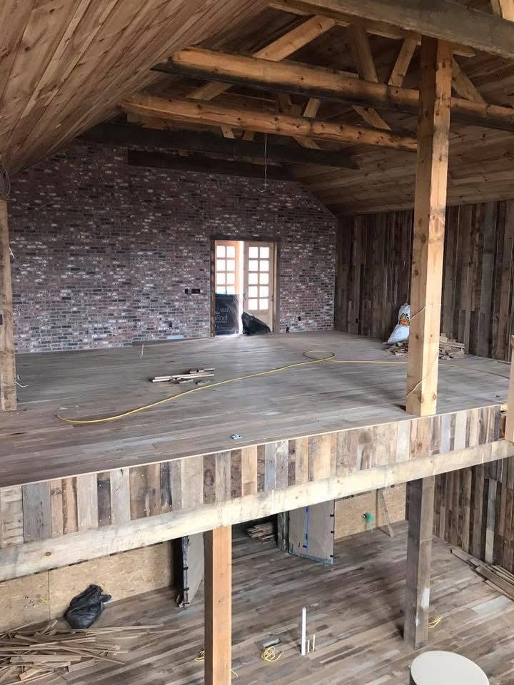 Upper loft level with finished hardwood flooring during a barn renovation project