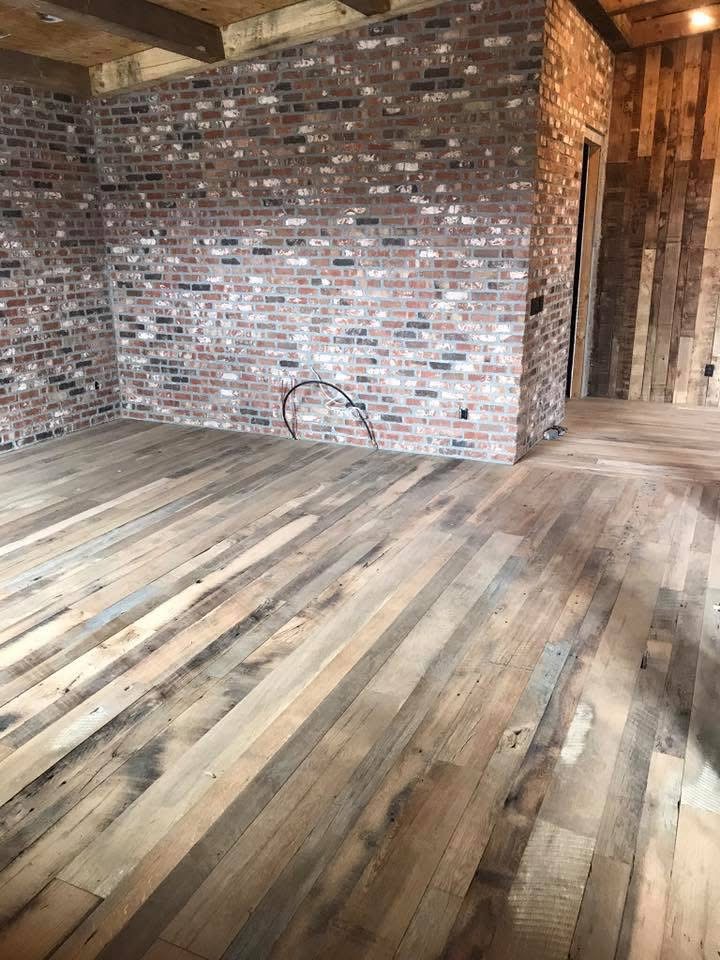 Reclaimed plank flooring with natural variation beside exposed brick walls